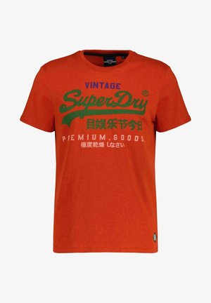 Oranje T-shirt met korte mouwen met de tekst "Vintage SuperDry Premium Goods" in blauw, groen en wit, plus Japanse karakters op de voorkant.