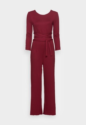 Combinaison bordeaux à manches longues, col rond et taille ceinturée. Confectionnée dans un tissu lisse et doux avec un design à jambes larges.