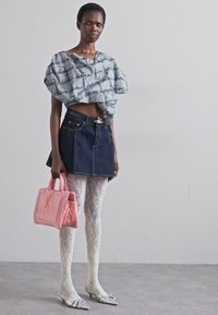 Μαύρο και άσπρο καρώ κοντό μπλουζάκι, σκούρα τζιν μίνι φούστα, λευκό δαντελένιο καλσόν, ασημένια μυτερά παπούτσια και ροζ δερμάτινη τσάντα με επένδυση.