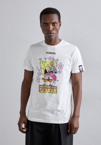 Tricou alb din bumbac, cu un imprimeu grafic colorat al unui personaj de desene animate, având textul "NU MI-E FRICĂ SĂ FIU PATAT". Mâneci scurte, decolteu rotund.
