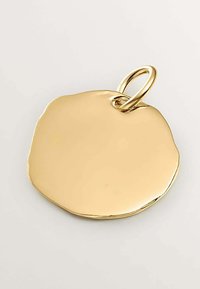 Pendiente dorado redondo con superficie pulida y borde irregular, con un lazo metálico para su sujeción. Textura suave, acabado brillante.