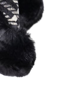 Pantofole nere pelose con un morbido bordo in pelliccia sintetica e una tomaia lavorata a maglia con un motivo geometrico nei toni del nero e del grigio.