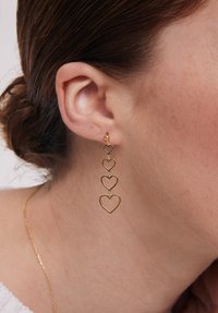 Złote kolczyki w kształcie czterech połączonych serc, z małą kulką na górze. Lekkie i wiszące w designie.