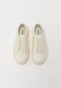 Baskets en cuir blanc avec bout arrondi, lacets plats et accents bleu clair. Semelle en caoutchouc texturée, design minimaliste, sans motifs visibles.