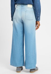 Helle, weit geschnittene Jeans aus Denim mit hoher Taille, zwei Gesäßtaschen und sichtbaren Nähten am Saum.