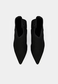 Μαύρες μποτάκια μέχρι τον αστράγαλο με μυτερή μύτη και λείο υφή. Διαθέτουν φερμουάρ στην εξωτερική πλευρά και κομψό, μινιμαλιστικό σχέδιο.