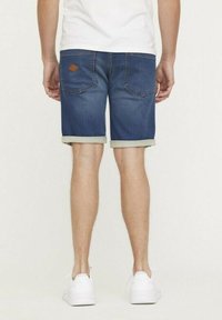 Donkerblauwe denim shorts met een opgerolde zoom, voorzien van achterzakken en een klein bruin logo-label op de tailleband.