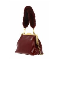 Sac à main en cuir verni bordeaux avec une monture métallique dorée, une bandoulière en chaîne et une poignée en fausse fourrure. Design texturé avec une légère brillance.