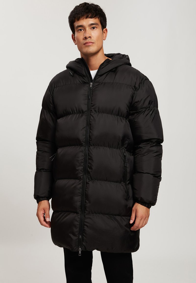 Czarna puchowa kurtka z kapturem, z pikowanym wzorem, przednim zamkiem błyskawicznym i elastycznymi mankietami. Długość do połowy uda z bocznymi kieszeniami.