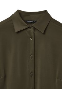 Camicia verde oliva con collo alla coreana, caratterizzata da una chiusura con bottoni e un tessuto liscio e strutturato. L'etichetta riporta "CALLIOPE", taglia S.