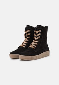 Stivaletti neri in suede con lacci beige, suola in gomma testurizzata, chiusura con zip e cuciture decorative lungo i lati.