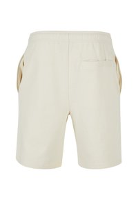 Shorts beiges à taille élastique avec une poche passepoilée arrière et des poches latérales, présentés sur un fond blanc.