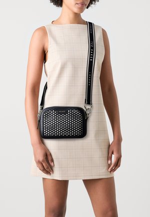 Zwarte schoudertas met een getextureerde, studded voorkant, rechthoekige vorm en zilveren hardware, voorzien van een verstelbare strap met merknaam.