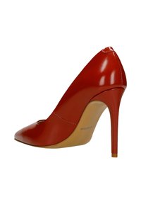 Czerwony lakierowany szpilkowy but z ostrym noskiem i wycięciem. Obcas jest smukły i ma około 10 cm wysokości.
