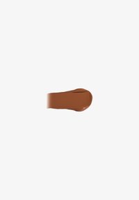 Brown liquid foundation with a creamy texture, applied in a smooth line. The color is warm medium brown, suitable for a variety of skin tones.