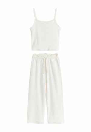 Weißes ärmelloses, kurz geschnittenes Tanktop, kombiniert mit hoch taillierten, weit geschnittenen Hosen mit elastischem Bund und Kordelzug.