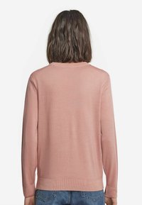 Ljusrosa tröja med långa ärmar, rund halsringning och ribbade muddar. Slät textur, minimalistisk design och rak nederkant.