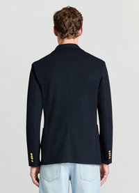 Blazer bleu marine en tissu lisse avec une coupe ajustée. Comprend deux poches latérales et des boutons dorés sur le revers de manche. Design classique à revers.