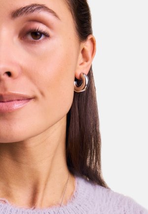 Pendientes de aro en tono plateado con un acabado liso y pulido. Formas curvas e interconectadas crean un diseño moderno. Adecuados para diversas ocasiones.