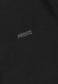 Czarna bawełniana koszulka z gładką teksturą i subtelnym, szarym logo "PROSTO." wydrukowanym w okolicach górnego lewego rogu. Prosty i minimalistyczny design.