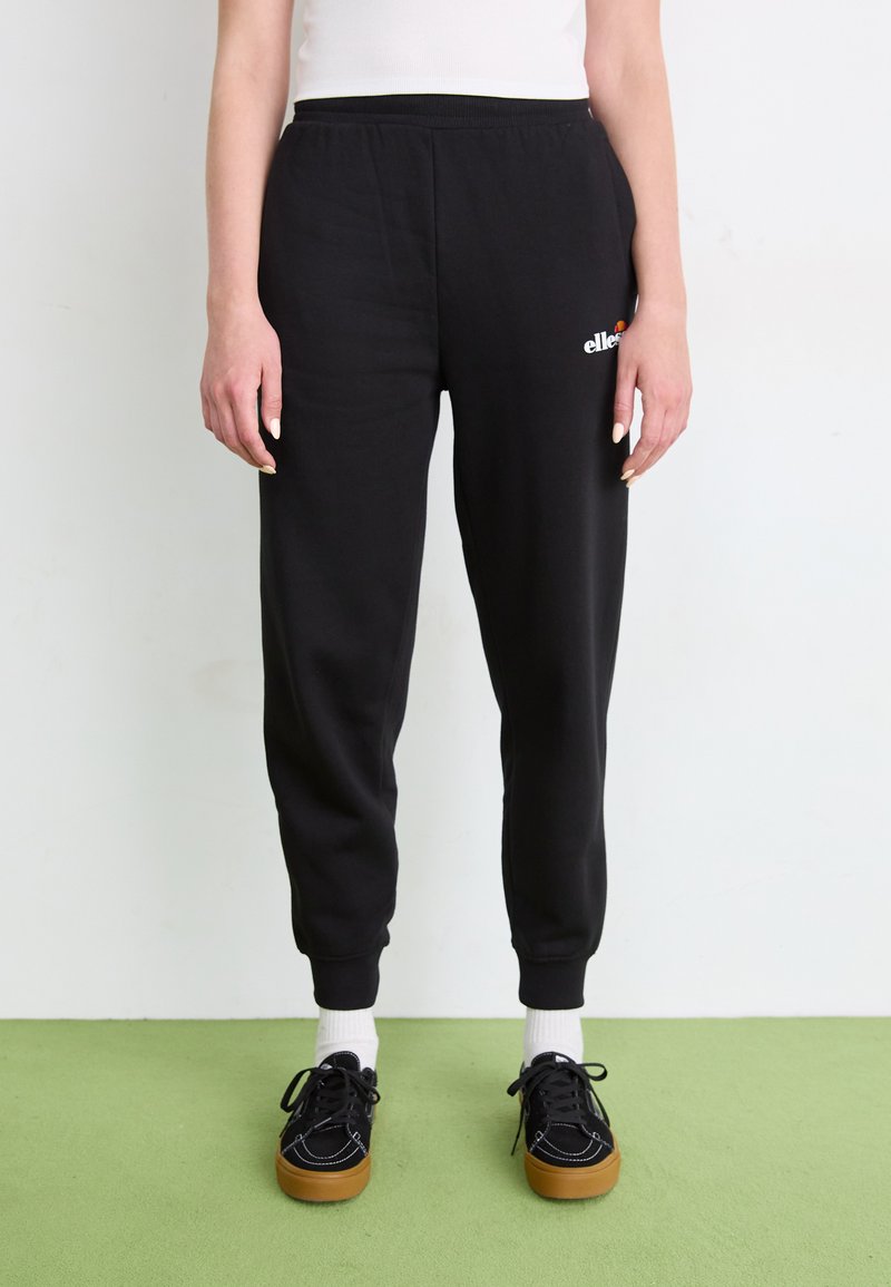 Zwarte jogpant met een ontspannen pasvorm, elastische tailleband, geborduurde enkels en witte logo details op de linkse heup. Zacht katoenmateriaal.