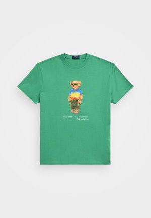 Zielony krótki t-shirt z nadrukiem na przodzie przedstawiającym misia w okularach przeciwsłonecznych, kolorową koszulką polo, spodnie typu cargo i sandały.