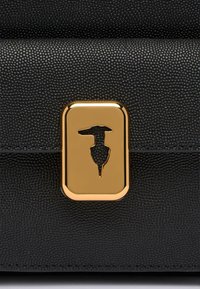 Czarna torebka z fakturowanej skóry z błyszczącym złotym kwadratowym zapięciem w kształcie sylwetki. Kompaktowy prostokątny kształt z zagiętym klapą.