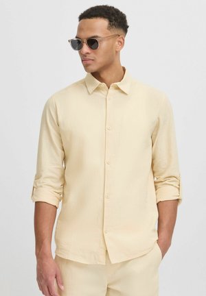 Light yellow button-up shirt in lightweight fabric with rolled sleeves and collar. Features a straight hem and subtle texture.