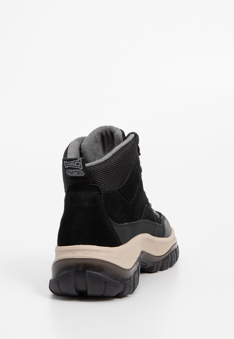 Baskets montantes noires avec tige en daim et textile. Présente une semelle épaisse et un col rembourré, avec une semelle intermédiaire beige en contraste.