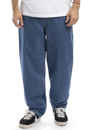 Blue denim jeans with a relaxed fit, visible seams, and pockets. Paired with black and white sneakers featuring a low profile.