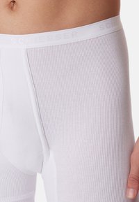 Vita ribbade boxerkalsonger med en mjuk elastisk midjeband med varumärket "SCHIESSER" i ljusgrått. Slät textur.