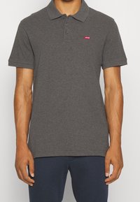Polo shirt gris foncé en coton, avec un col, trois boutons et un petit logo rouge Levi's sur la poitrine.