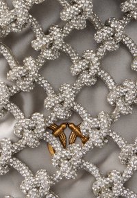 Ασημένιο διακοσμητικό δίχτυ με στρας σε σχήματα λουλουδιών σε λείο γκρι ύφασμα, με λεπτομέρειες πουλιών με χρυσές αποχρώσεις.