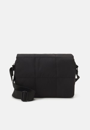 Sort rektangulær quiltet crossbody taske med justerbar rem, vist mod en ensfarvet hvid baggrund.