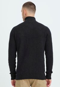 Donkergrijze gebreide coltrui met lange mouwen. Beschikt over een getailleerd ontwerp en textuurstof, gezien vanuit de achterkant.