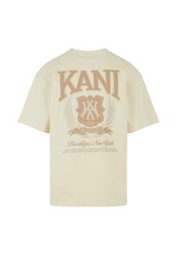 Crème-kleurig T-shirt met grote bruine "KANI" tekst en logo op de achterkant. Relaxte pasvorm, korte mouwen, zachte katoen stof.
