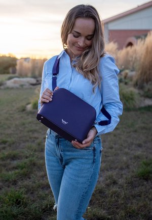 Lila Schultertasche mit glatter Textur, abgerundeter Form und verstellbarem Riemen. Verfügt über ein Logo auf der Vorderseite und metallische Akzente.