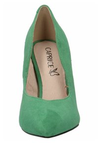 Chaussure à talons hauts en velours vert avec un bout pointu et un design découpé. À l'intérieur, on voit la marque "CAPRICE" sur une semelle intérieure beige. Semelle extérieure noire.