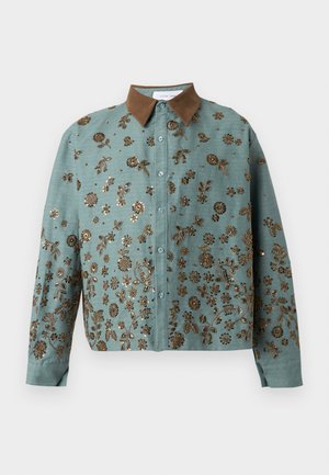 Chemise boutonnée bleu sarcelle avec col marron, décorée d'une broderie florale en perles dorées complexe couvrant le devant et les manches.