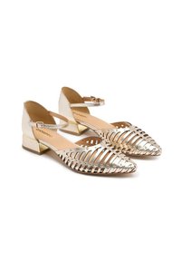 Sandalias metálicas doradas con diseño recortado, punta cerrada, correa en el tobillo y tacón bajo. Textura suave con acentos brillantes.