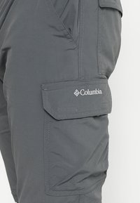 Harmaat cargo-housut kevyestä materiaalista, joissa on sivutasku, ommeltuja yksityiskohtia ja valkoinen Columbia-logo.