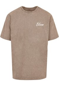 Īsām piedurknēm, apaļā kakla krekls izbalējušā brūnā krāsā. Ar nelielu balto "Bloom" logo kreisajā krūšu pusē.