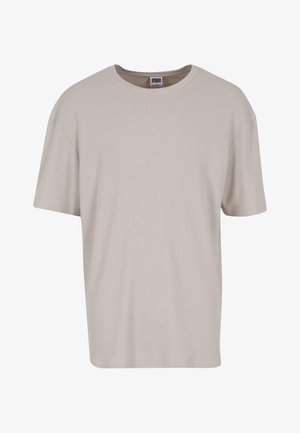 Hellbeige T-Shirt mit kurzen Ärmeln aus strukturiertem Stoff, mit Rundhalsausschnitt und lockerer Passform. Keine sichtbaren Muster oder Hardware.