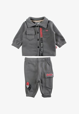 Tenue grise pour enfant comprenant un haut boutonné avec deux poches, et un pantalon avec une taille élastique et une poche latérale. Comprend des détails avec le logo de la marque.