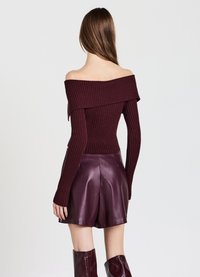 Burgunderfarbiges, geripptes Off-Shoulder-Oberteil, kombiniert mit hoch sitzenden Leder-Shorts, die eine glatte Textur und eine enganliegende Silhouette zeigen.