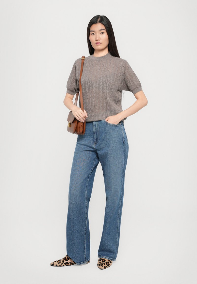 Top corto a maniche, in maglia marrone testurizzata, abbinato a jeans a vita alta di colore blu chiaro con gamba larga e tacchi a punta con stampa leopardata. Borsa a spalla marrone.