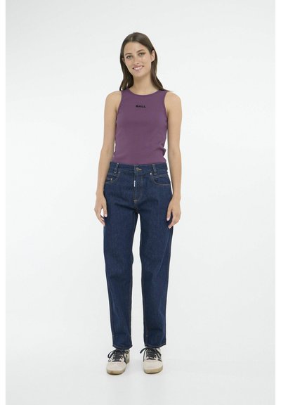 Top con canotta viola con testo "BALL", abbinato a jeans dritti blu scuro. Il modello indossa sneakers beige e nere. Sfondo bianco semplice.