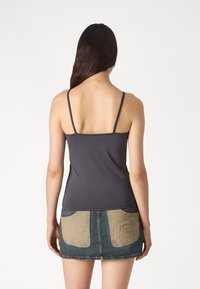 Grå tettsittende tanktopp med tynne stropper, kombinert med et denimskjørt med brune lommer og frayed kant.