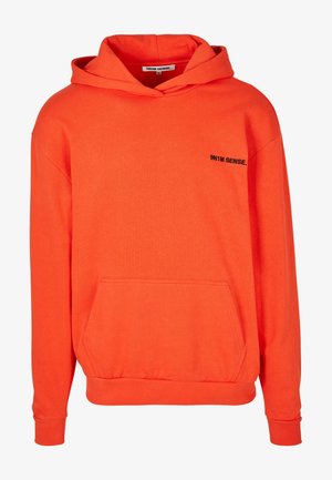 Oranje hoodie met een voorzak, trekkoord capuchon, ribbenmanchetten en een klein zwart logo op de borst. Zachte katoenen stof, relaxte pasvorm.