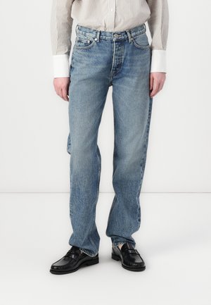 Lys blå denimjeans med en avslappet passform, med fem lommer, beltehemper og en falmet tekstur. Kombinert med svarte loafers.